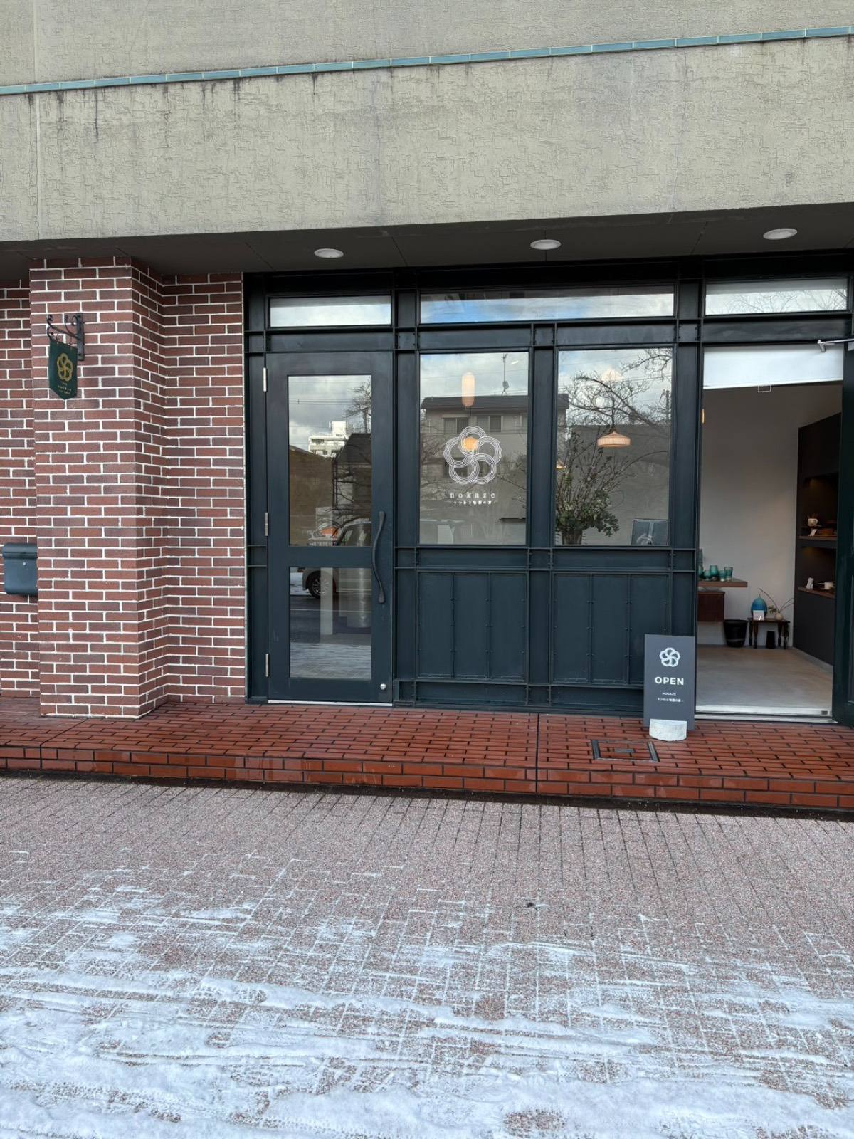雪の残る朝の nokaze 外観と OPEN の看板 / The nokaze storefront on a snowy morning with the OPEN sign out