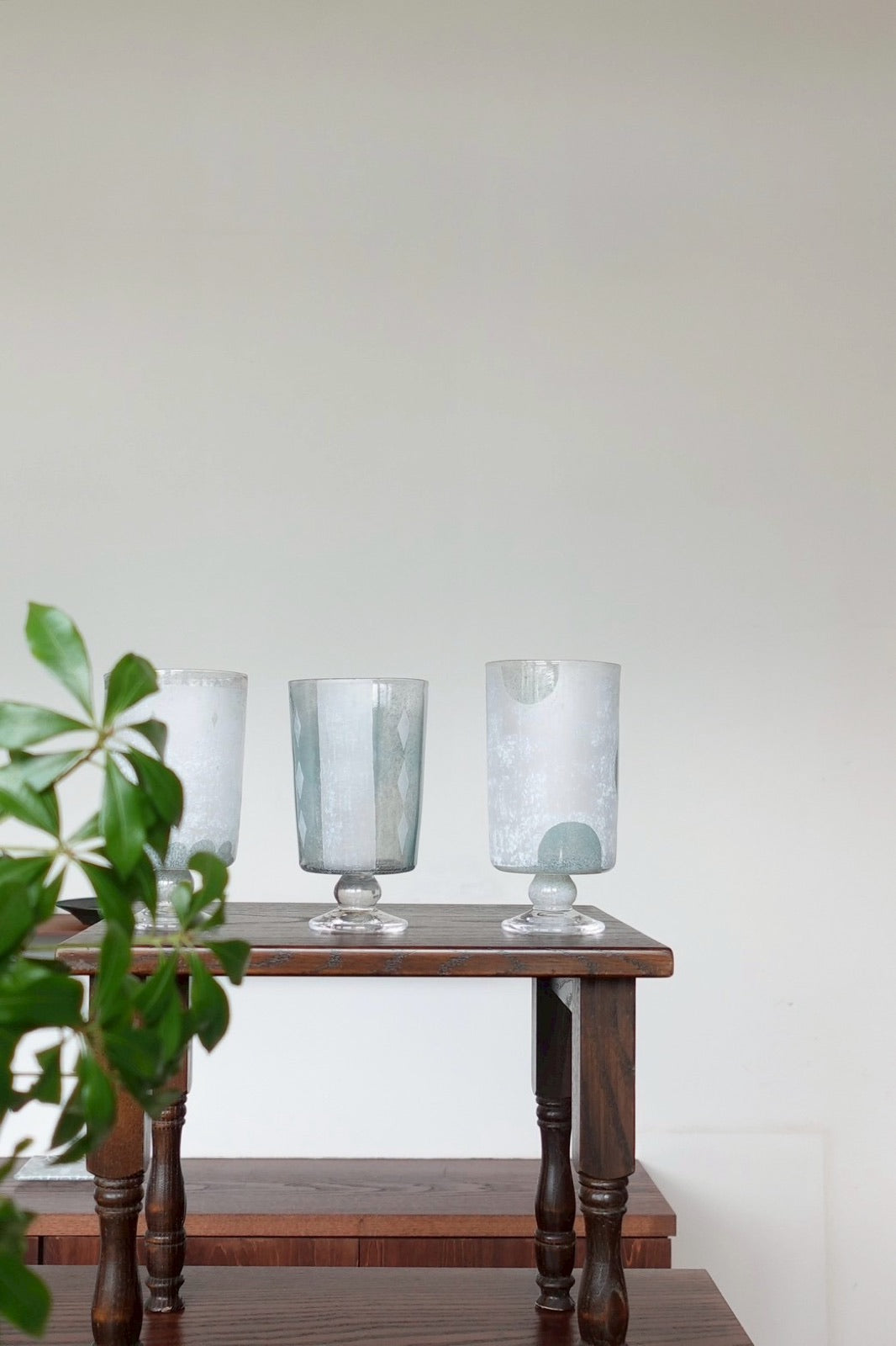 木の棚に並ぶ、すりガラスの脚付きグラス / Frosted footed glasses on a wooden shelf