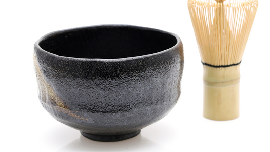 黒楽の茶碗と竹の茶筅。艶のある黒釉にざらついた凹凸があり、口縁がゆるやかに波打つ