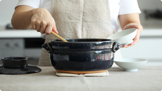 Serving freshly cooked rice from a tenmoku five-go donabe rice pot, its base left as bare clay