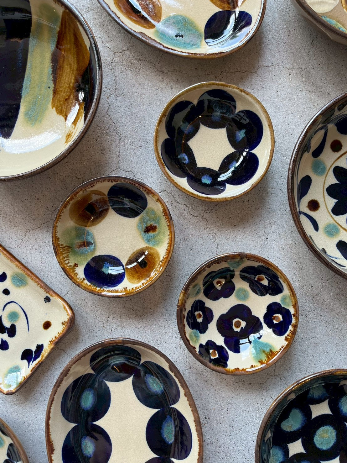 Okinawan yachimun plates and bowls on concrete, brushed with cobalt blue, green and amber on cream