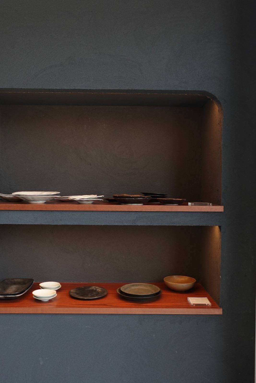 墨色の壁にくり抜いた棚と、黒と白の器 / Black and white plates in a rounded niche of a charcoal plaster wall